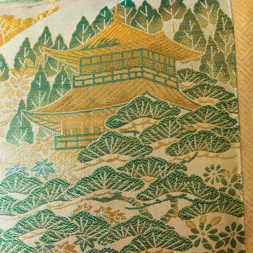 Close up of nishijin silk gold obi cushion in gold and green, temple and pine forest.
