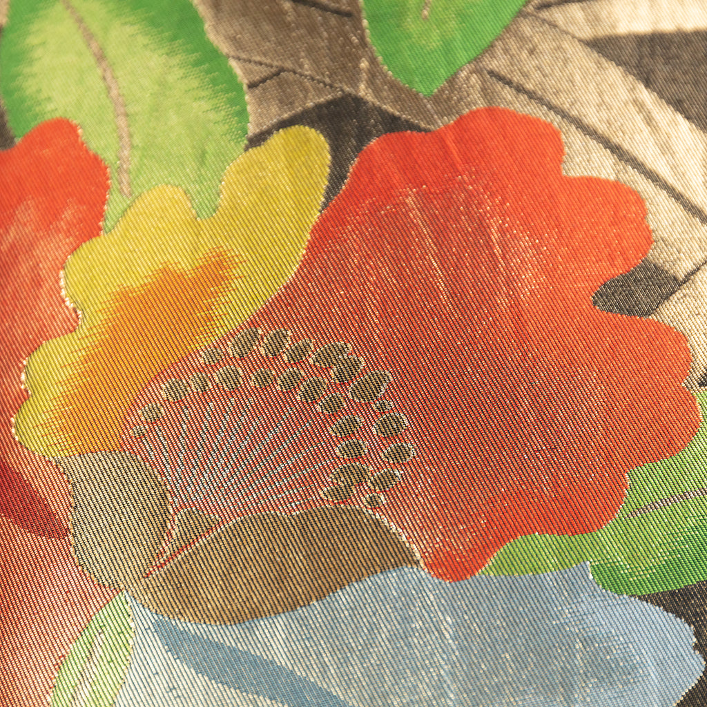 Close up of a camellia flower motif on a vintage Japanese obi cushion in red, yellow, green, gold and black.