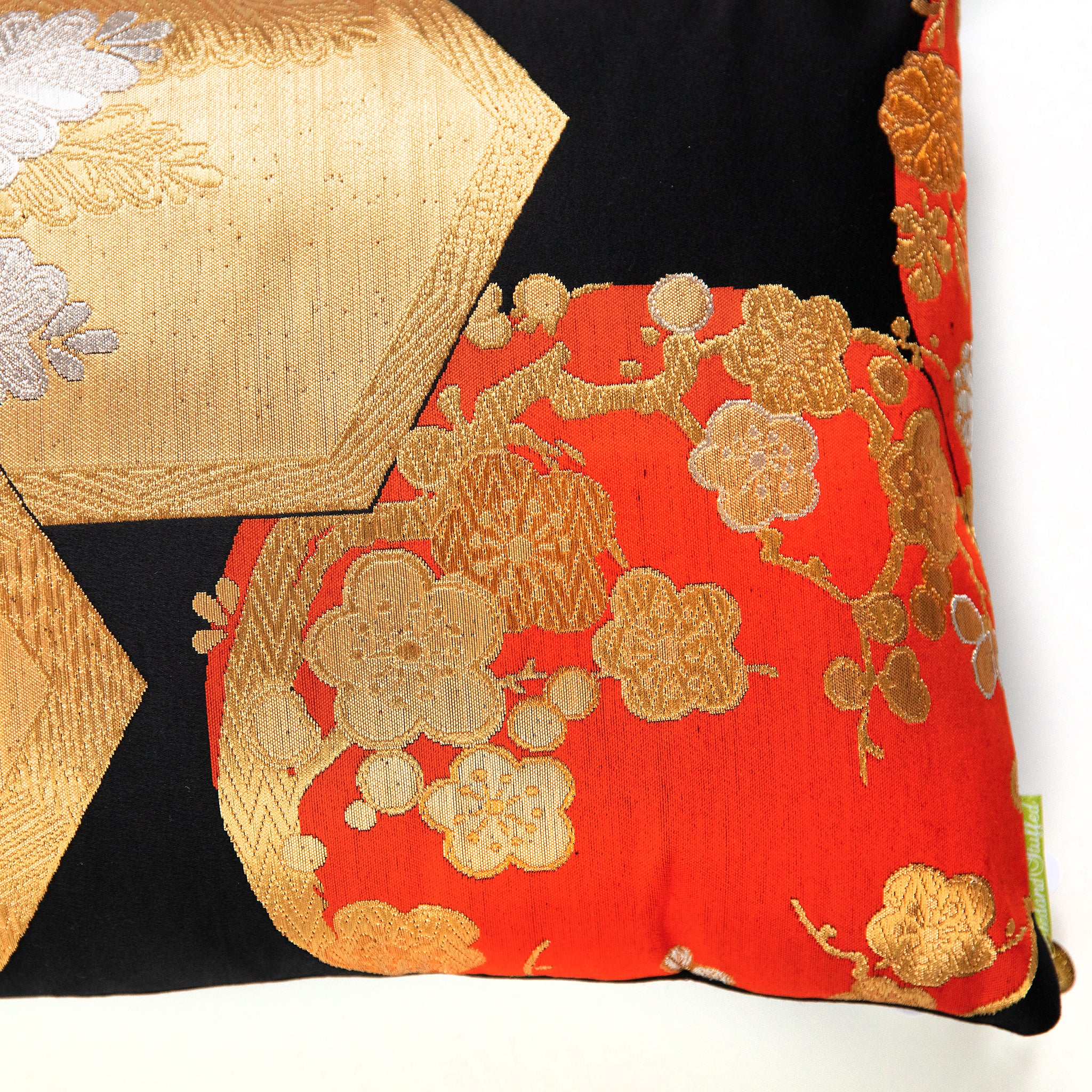 Detail of black silk obi pillow corner with orange and gold blossom pattern