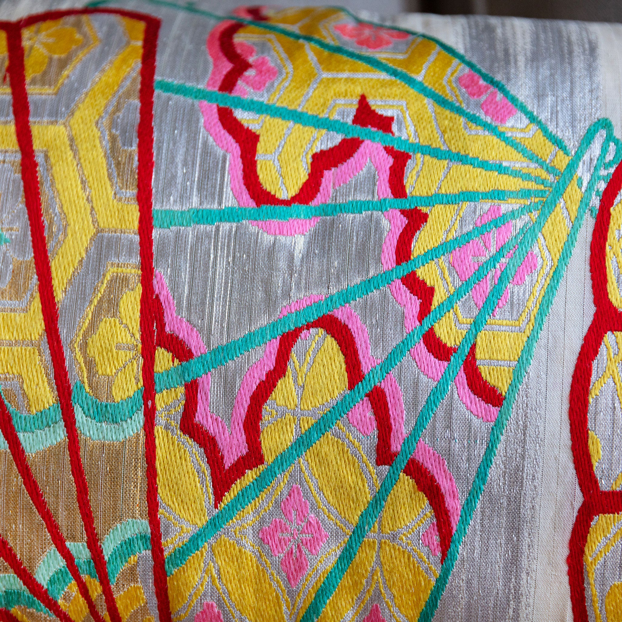 Close up detail of japanese bolster cushion made with 1950s silver maru obi with colourful fan designs.