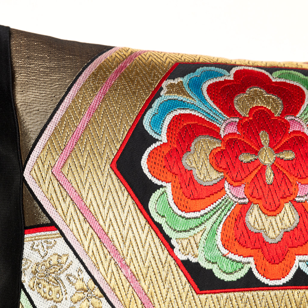 Close up detail of a gold vintage obi kimono cushion with hexagon pattern and a red hanabishi flower design.