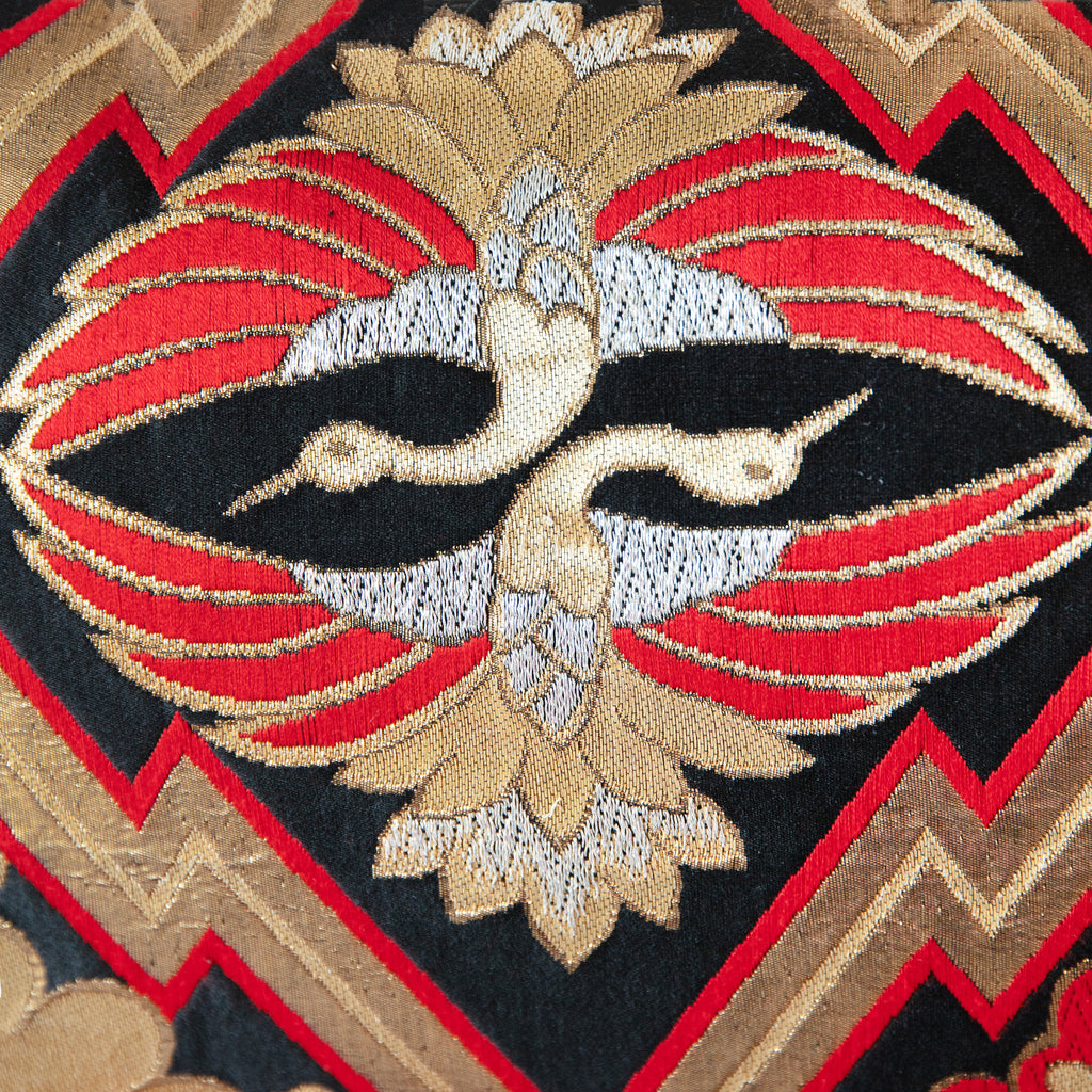 Detail of two crane motifs in gold, silver and red on a black vintage silk obi cushion.