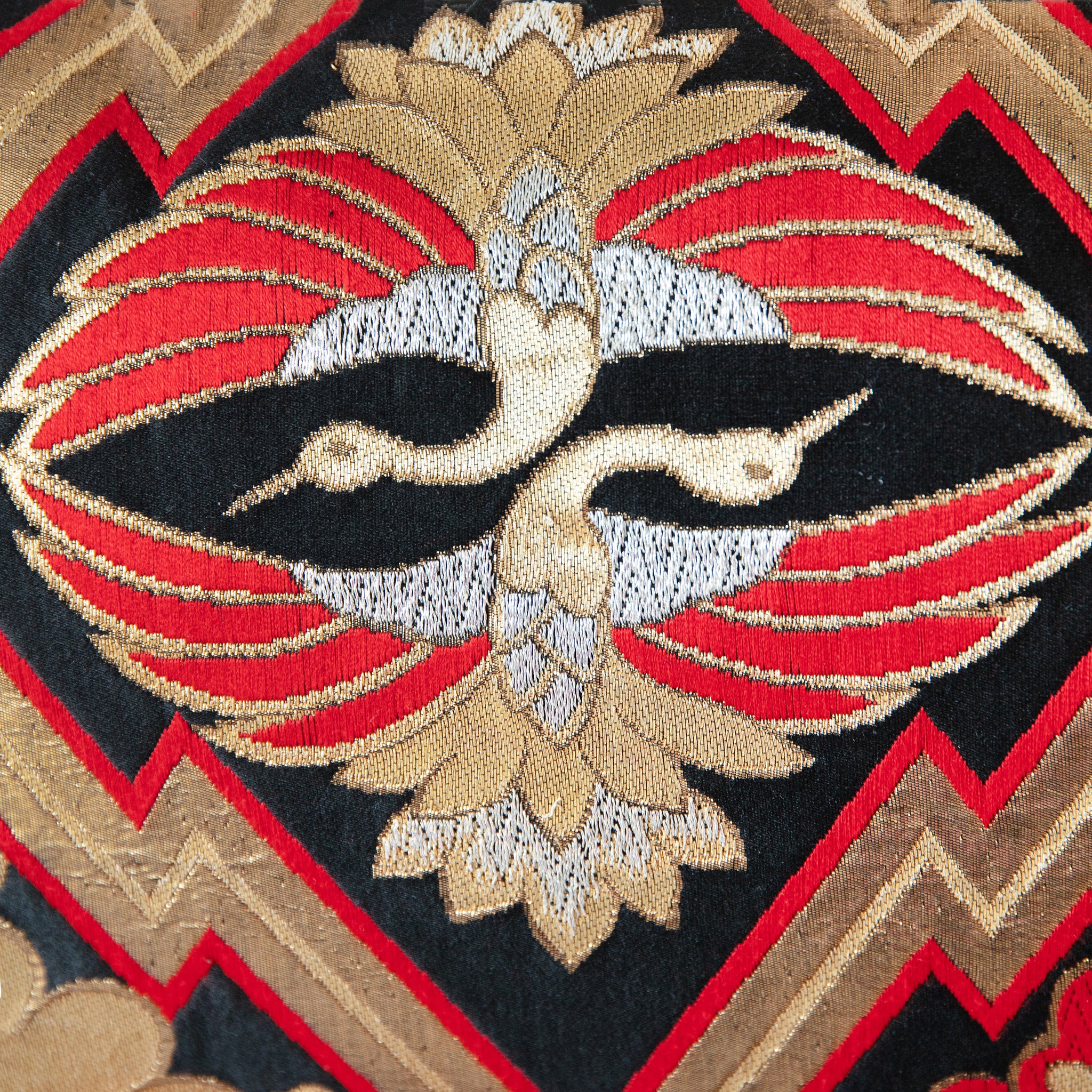 Detail of two crane motifs in gold, silver and red on a black vintage silk obi cushion.