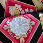 Close-up of pink silk fabric with gold accents and subtle textured weave on the pillow's corner detail