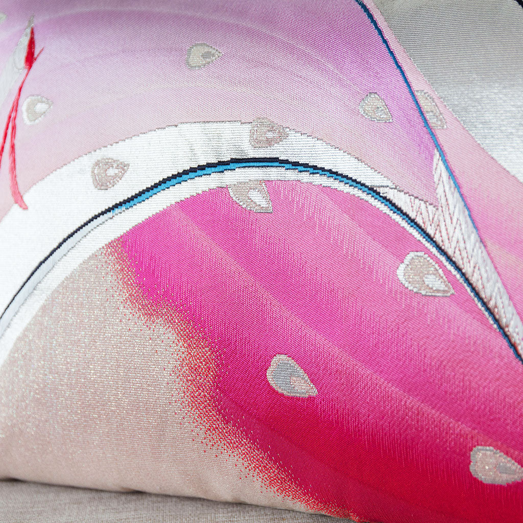 Close-up of pink silk fabric with intricate silver obi pattern, highlighting the delicate woven texture and shimmering