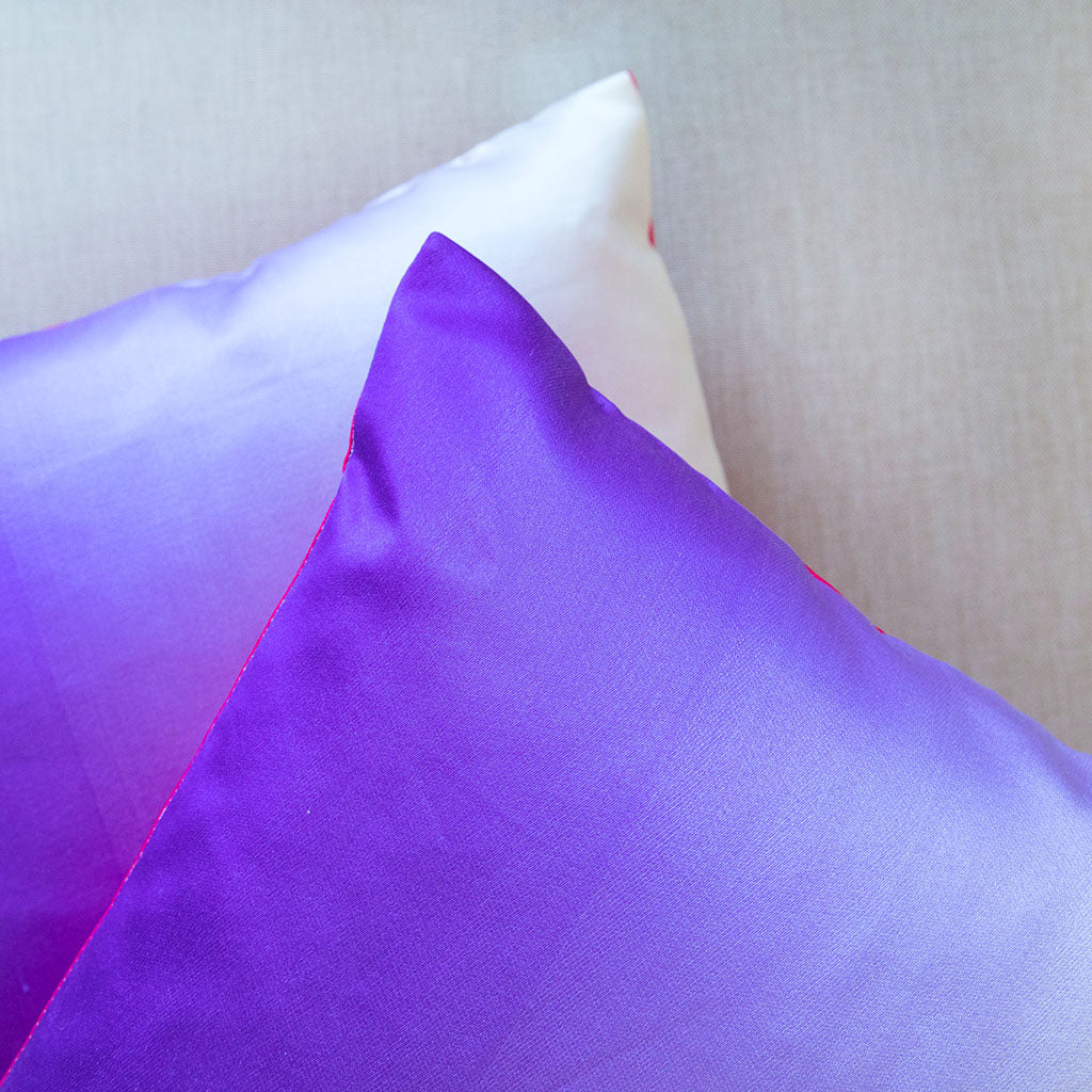 Detail of a purple corner of a silk cushion with a corner behind it from a purple ombre silk cushion.