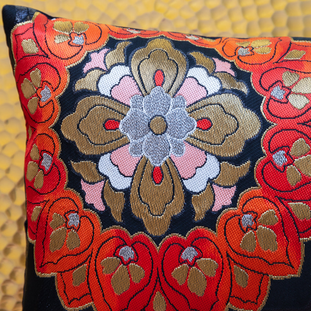 Detail of corner of black silk obi cushion with red, pink and gold floral motif.