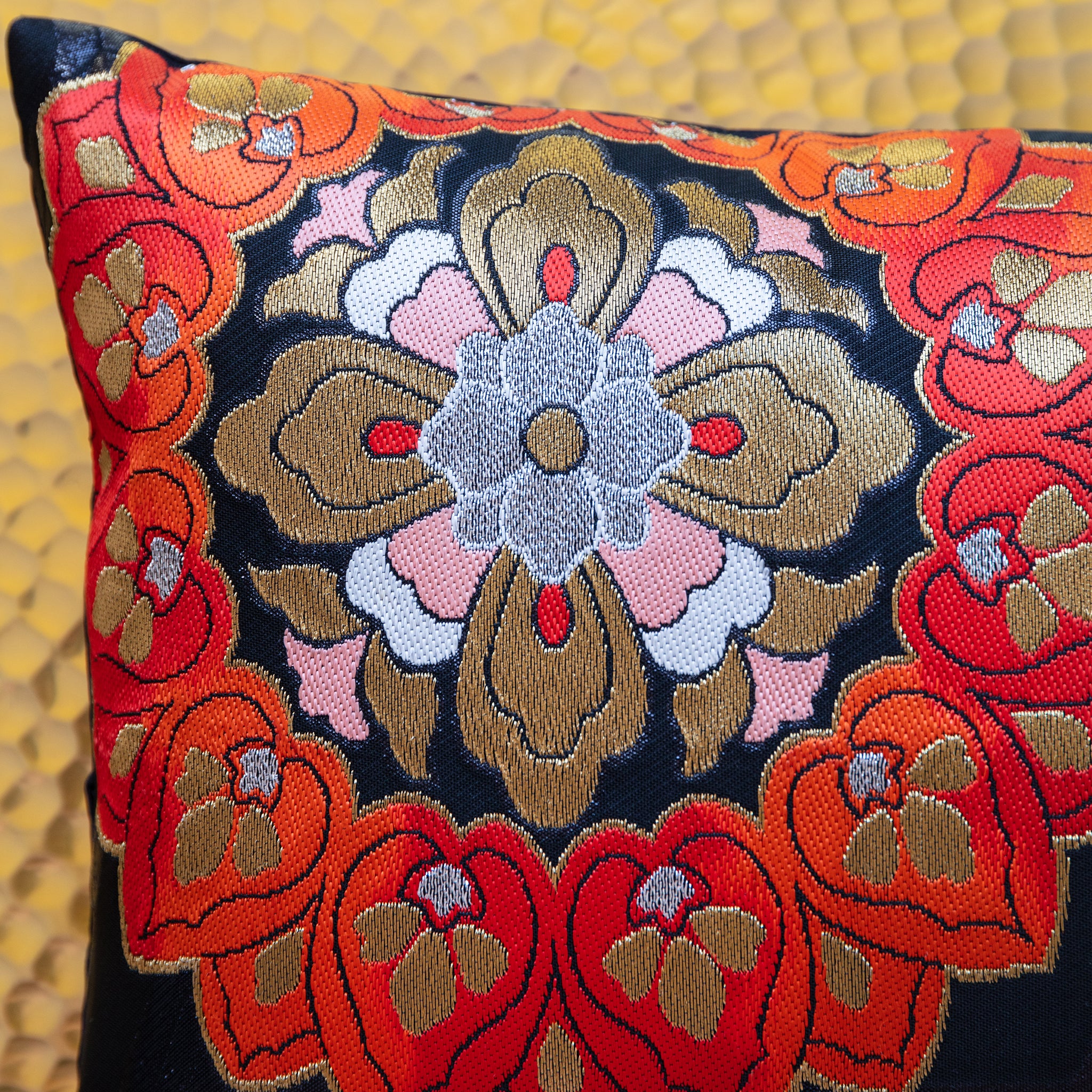 Detail of corner of black silk obi cushion with red, pink and gold floral motif.