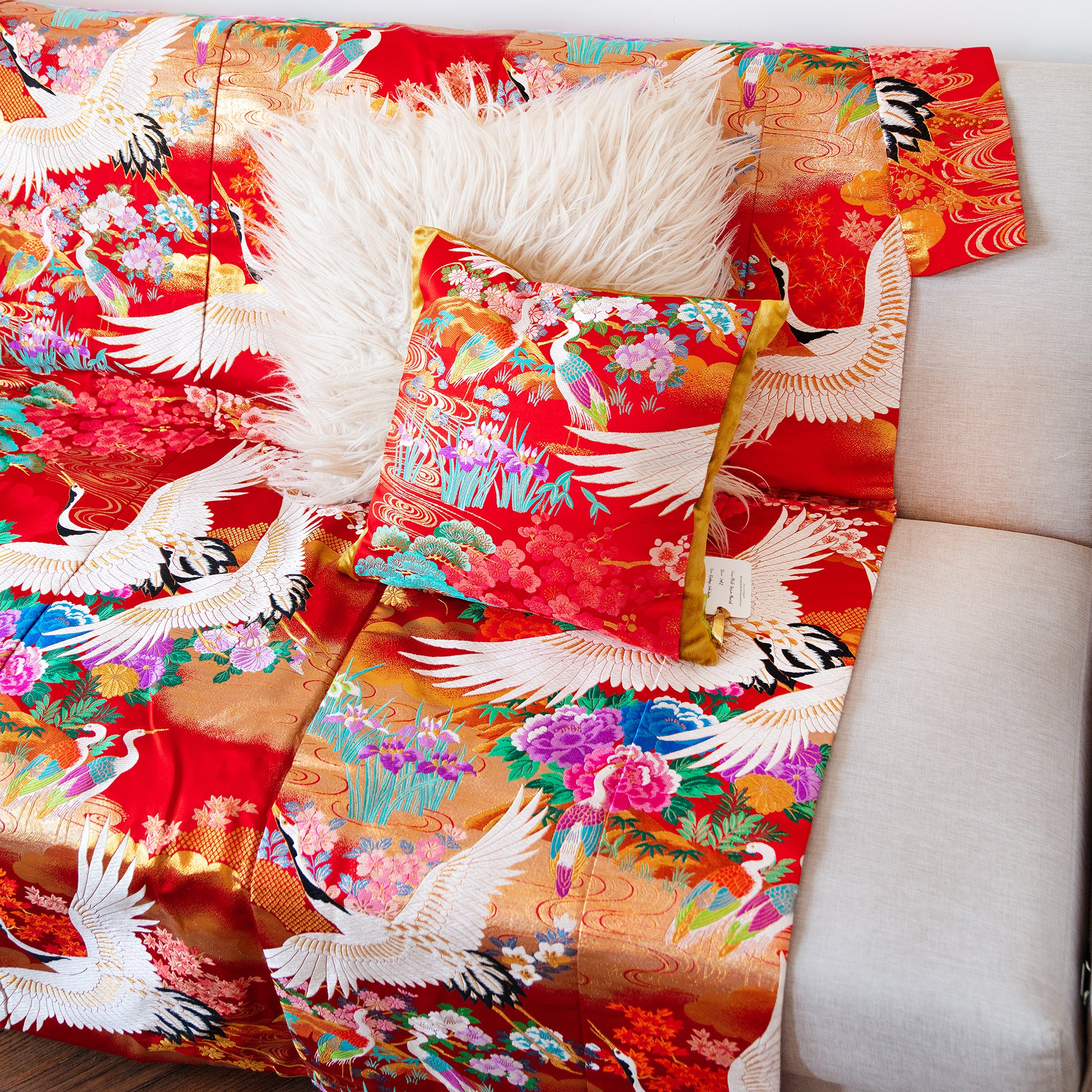 red silk vintage kimono throw with flowers and cranes with matching cushion on a sofa