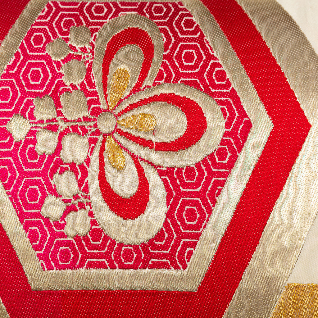 Close-up of red hexagon Kiri flower pattern on Obi cushion inside a hexagon motif and with repeating hexagons pattern background in gold.
