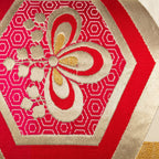 Close-up of red hexagon Kiri flower pattern on Obi cushion inside a hexagon motif and with repeating hexagons pattern background in gold.