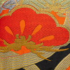 Close-up of red gold pine tree embroidery detail on black velvet cushion showing intricate stitching and textured fabric