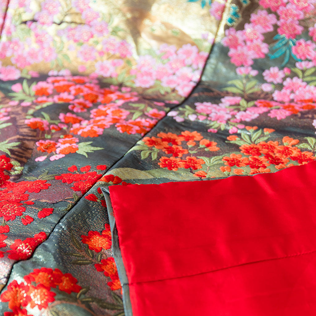 Close-up of vintage kimono-inspired embroidery details on the silk throw blanket's textured border and finishing stitches.