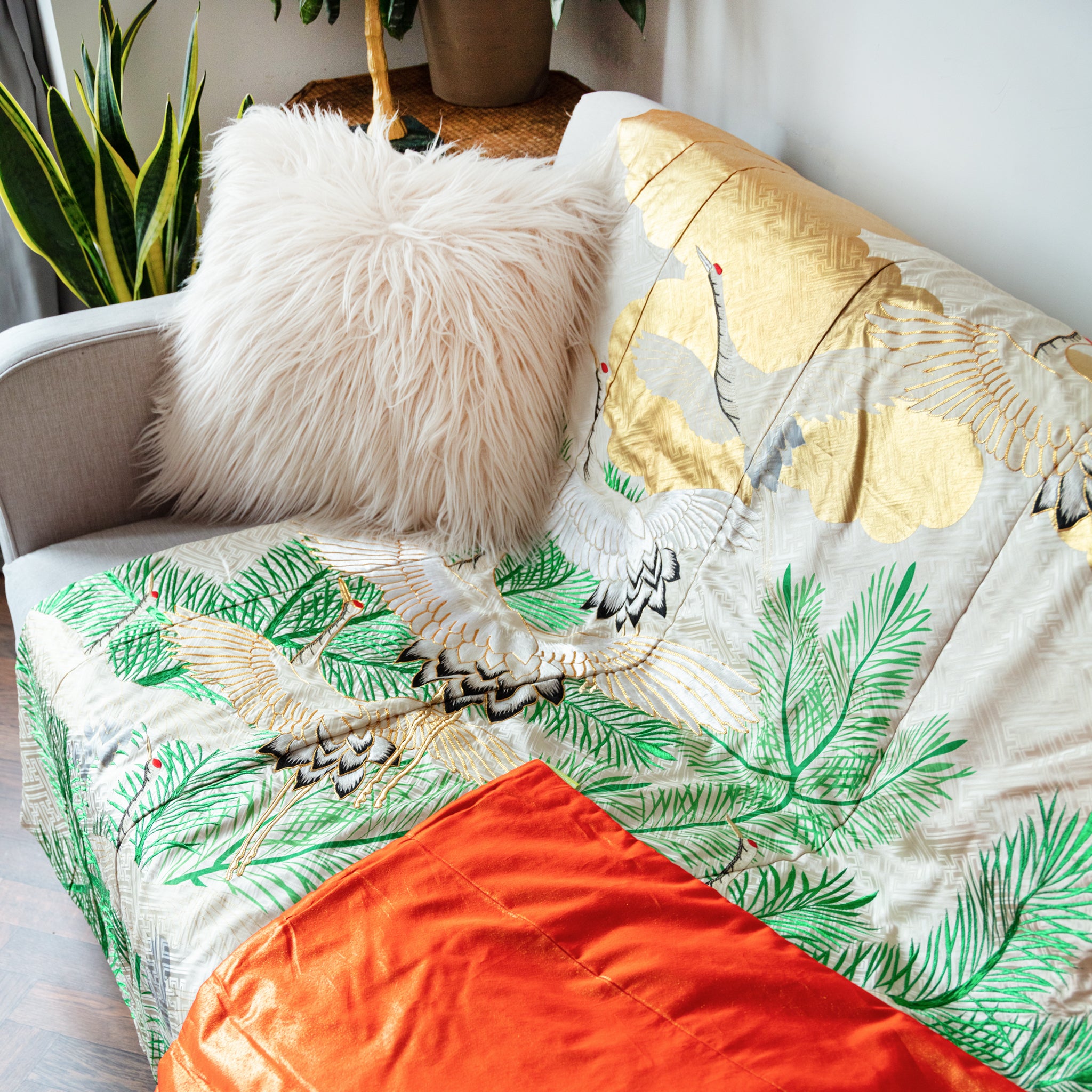 silk throw made from vintage kimono silk, cream, green and gold clouds, pines and cranes, on sofa, corner turned up to show orange reverse
