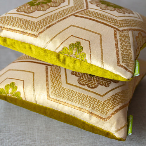 Side view of a stack of two small square 12 inch vintage gold obi cushions with fortune hexagons pattern and chartreuse velvet backs.
