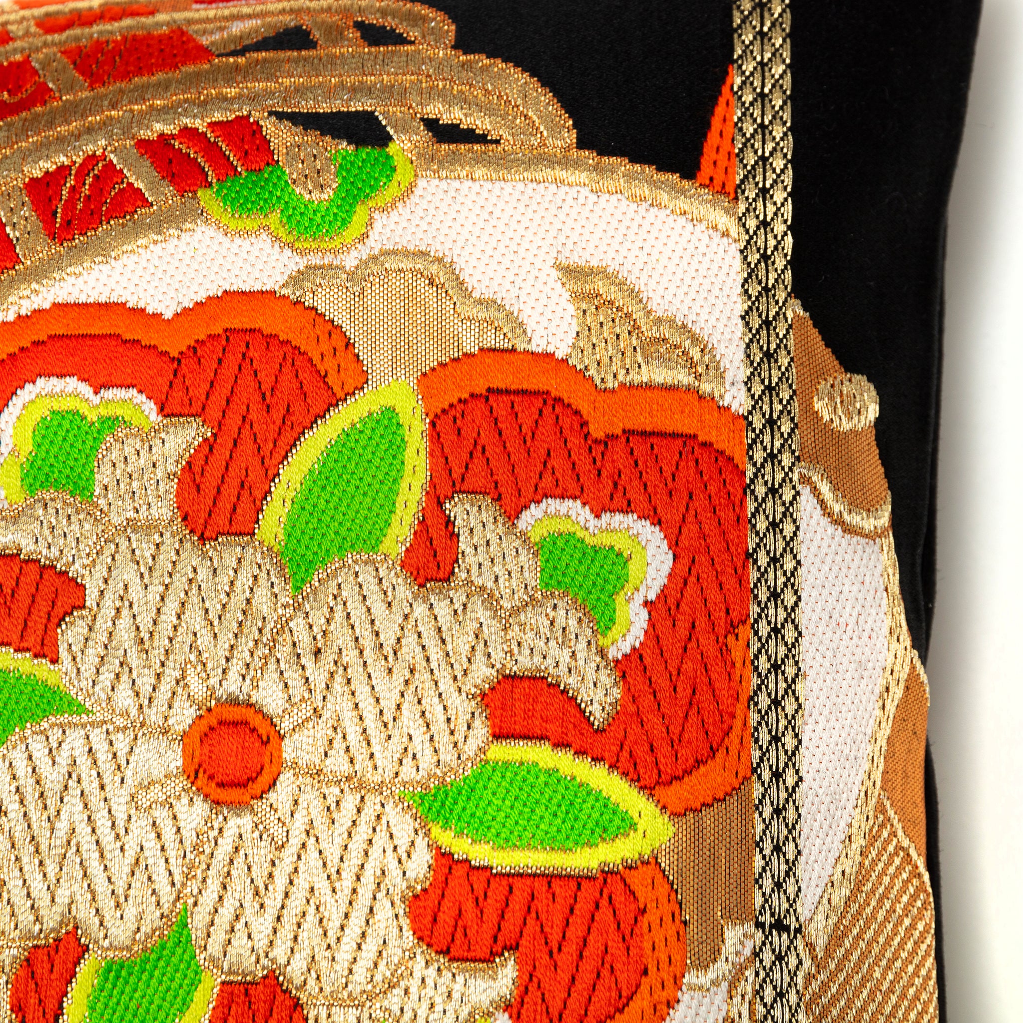 Close up detail of a woven silk Japanese obi with drum pattern and red and green accents