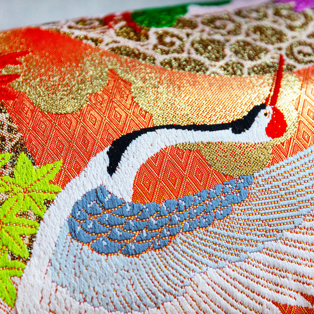 Close-up of vibrant kimono silk cranes embroidered onto lush blue velvet fabric, highlighting intricate stitching and