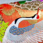 Close-up of vibrant kimono silk cranes embroidered onto lush blue velvet fabric, highlighting intricate stitching and