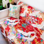 silk throw made from vintage kimono silk on a sofa. Red base, colourful flowers and white embroidered cranes.