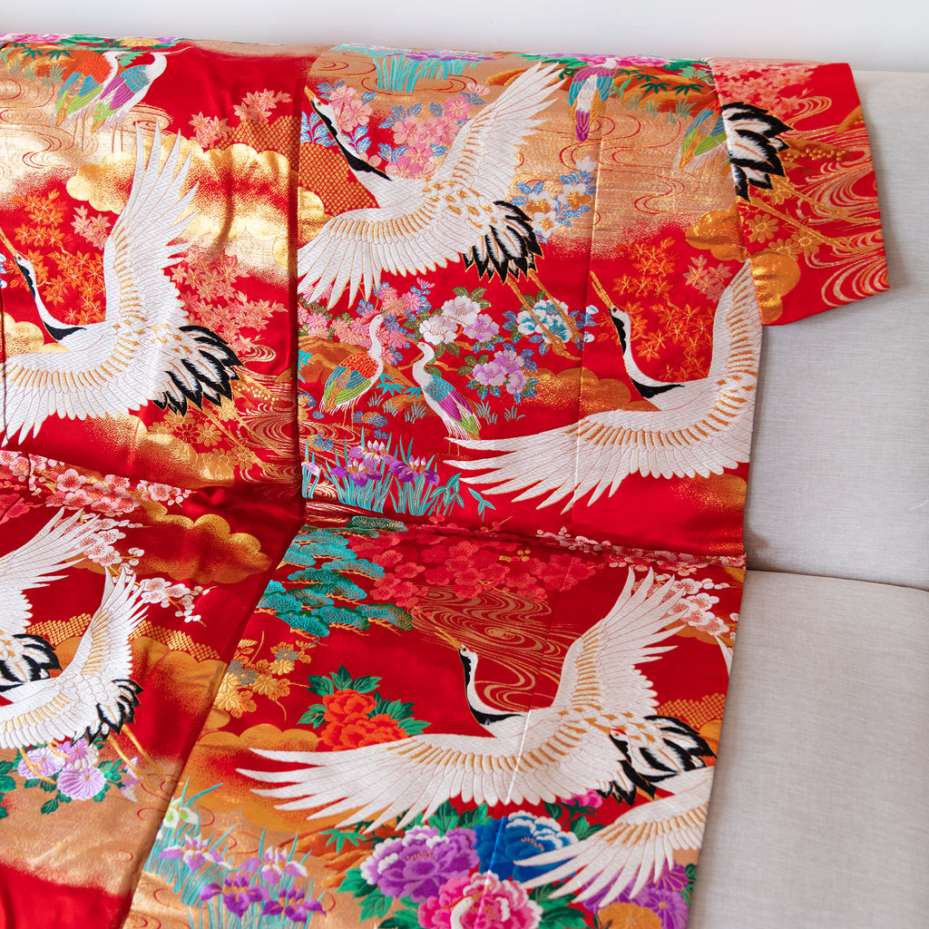silk throw in red, made from vintage kimono silk, white embroidered cranes, multicoloured flowers, showing collar edge of throw, on sofa