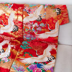 silk throw in red, made from vintage kimono silk, white embroidered cranes, multicoloured flowers, showing collar edge of throw, on sofa