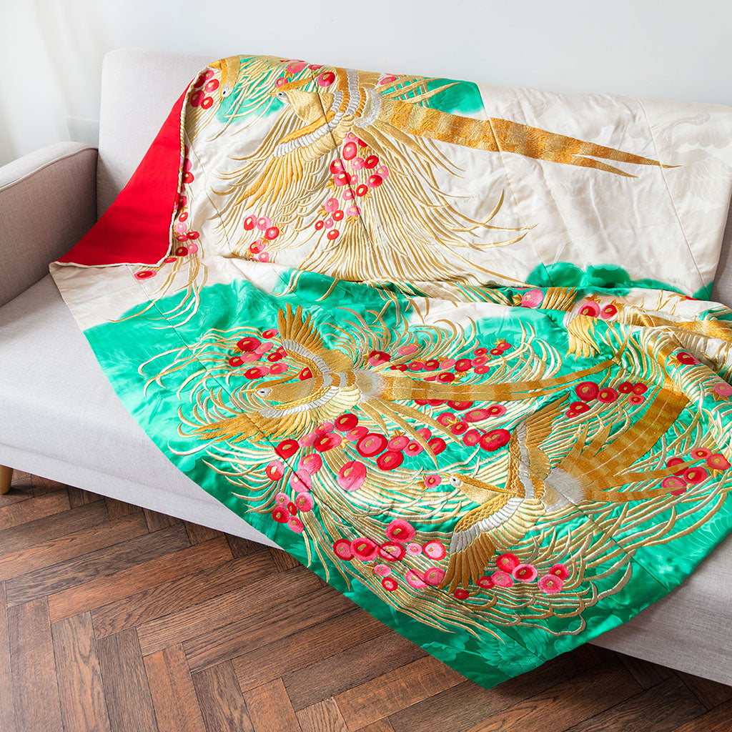 Close-up of intricate gold phoenix embroidery on the silk throw blanket’s corner, highlighting detailed vintage-style