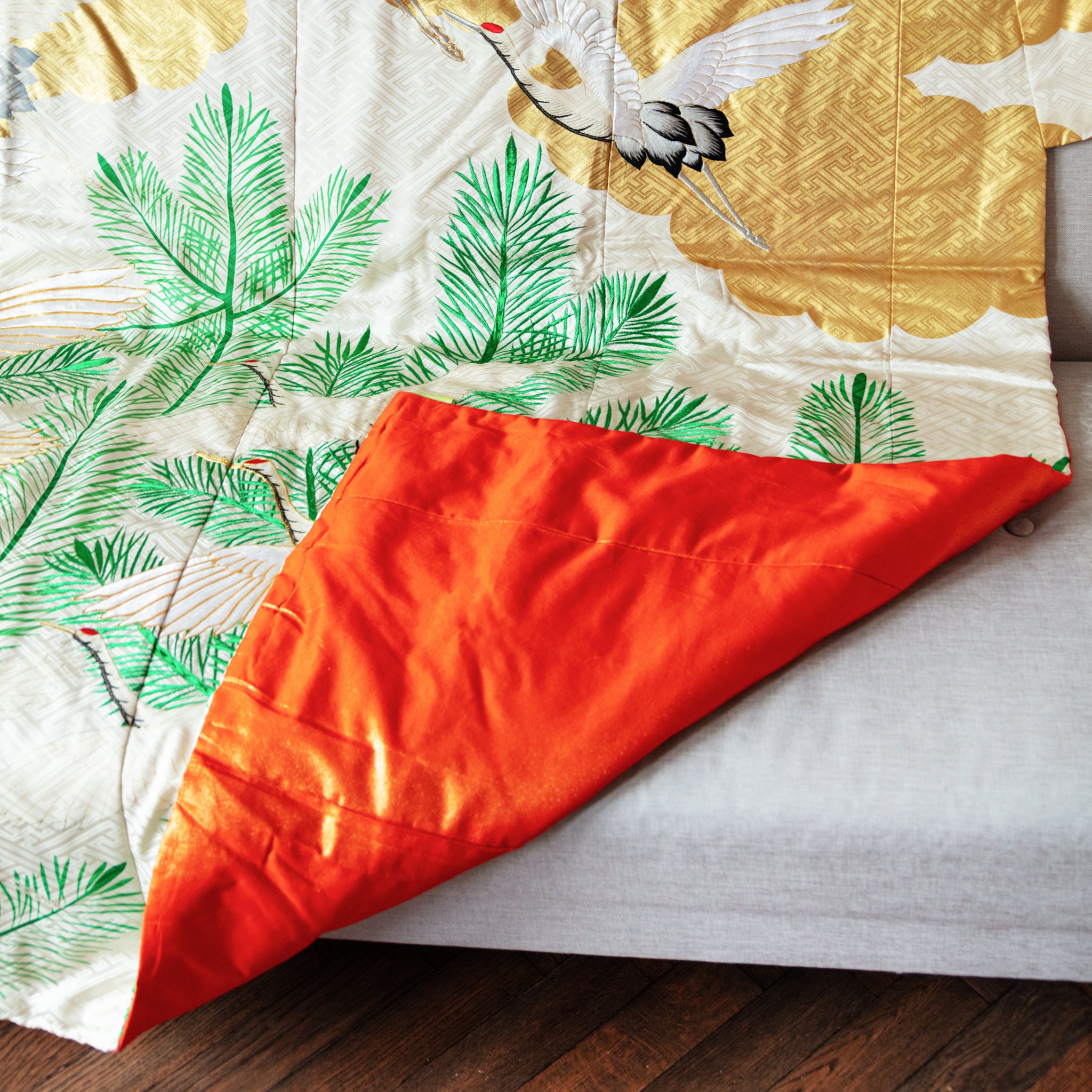 Cream silk throw made from vintage kimono silk with corner turned up to show orange silk lining, on sofa