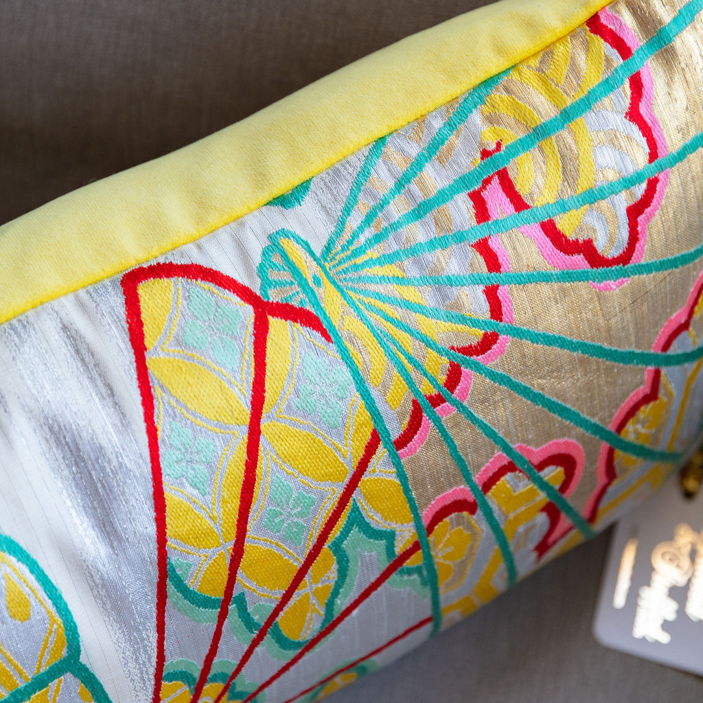 Close-up of yellow bolster cushion fabric featuring detailed silver kimono silk with oriental fan embroidery at a slight