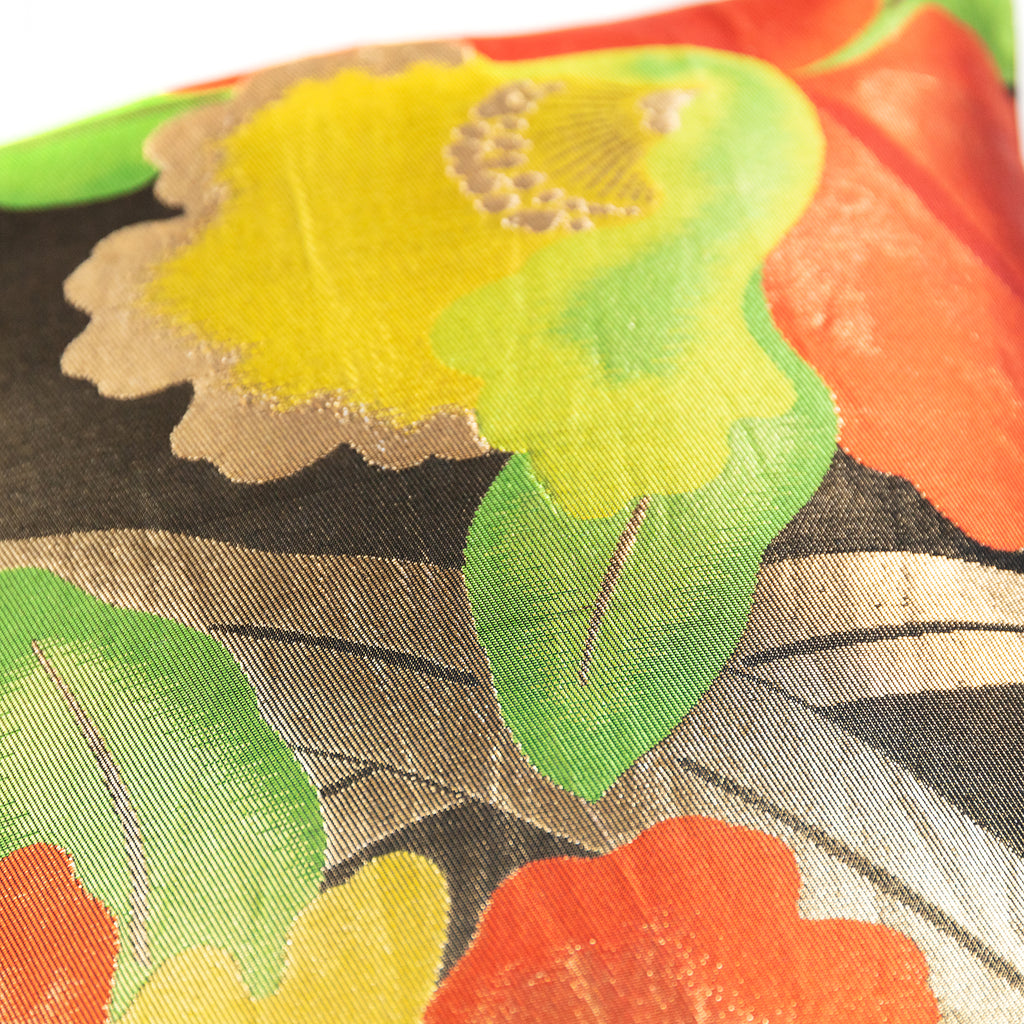 Yellow floral pattern on a vintage Japanese black silk obi cushion with green leaves and gold accents.