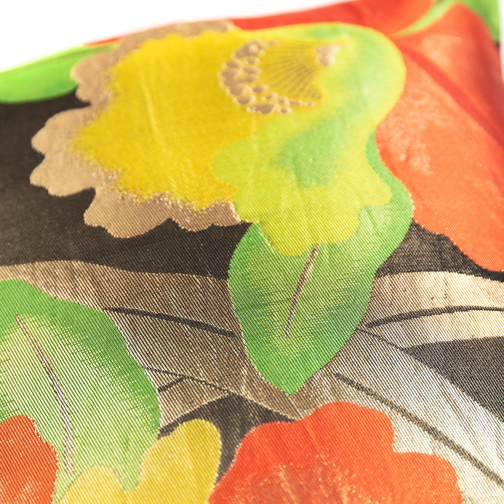 Yellow floral pattern on a vintage Japanese black silk obi cushion with green leaves and gold accents.